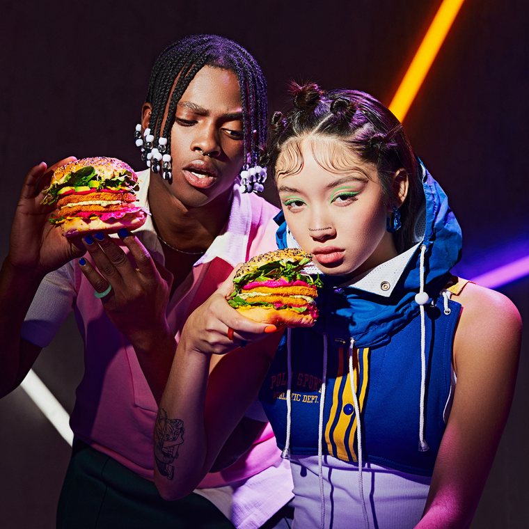 Dos modelos con hamburguesas bajo luces de neón